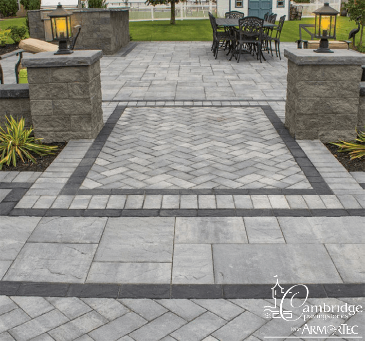 A grill and outdoor eating area with gray pavers in an inlay pattern.