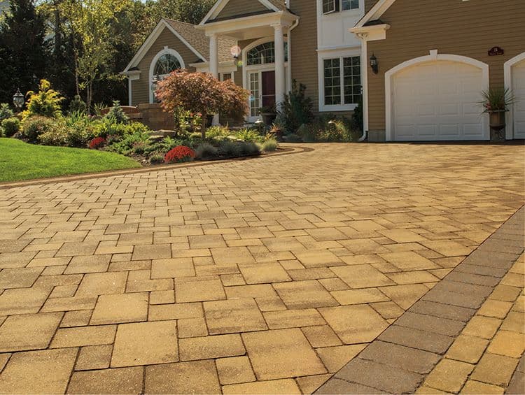 Closeup of a brown paver driveway leading up to a house.