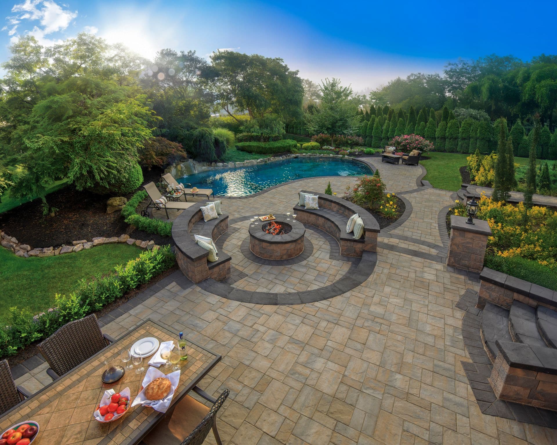 Pavers around an outdoor seating area, firepit, and pool.